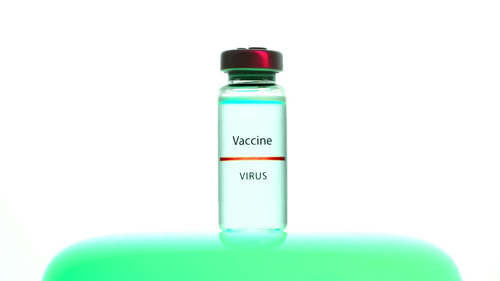 A close-up of a vaccine vial labeled 'Vaccine Virus' on a vibrant background.