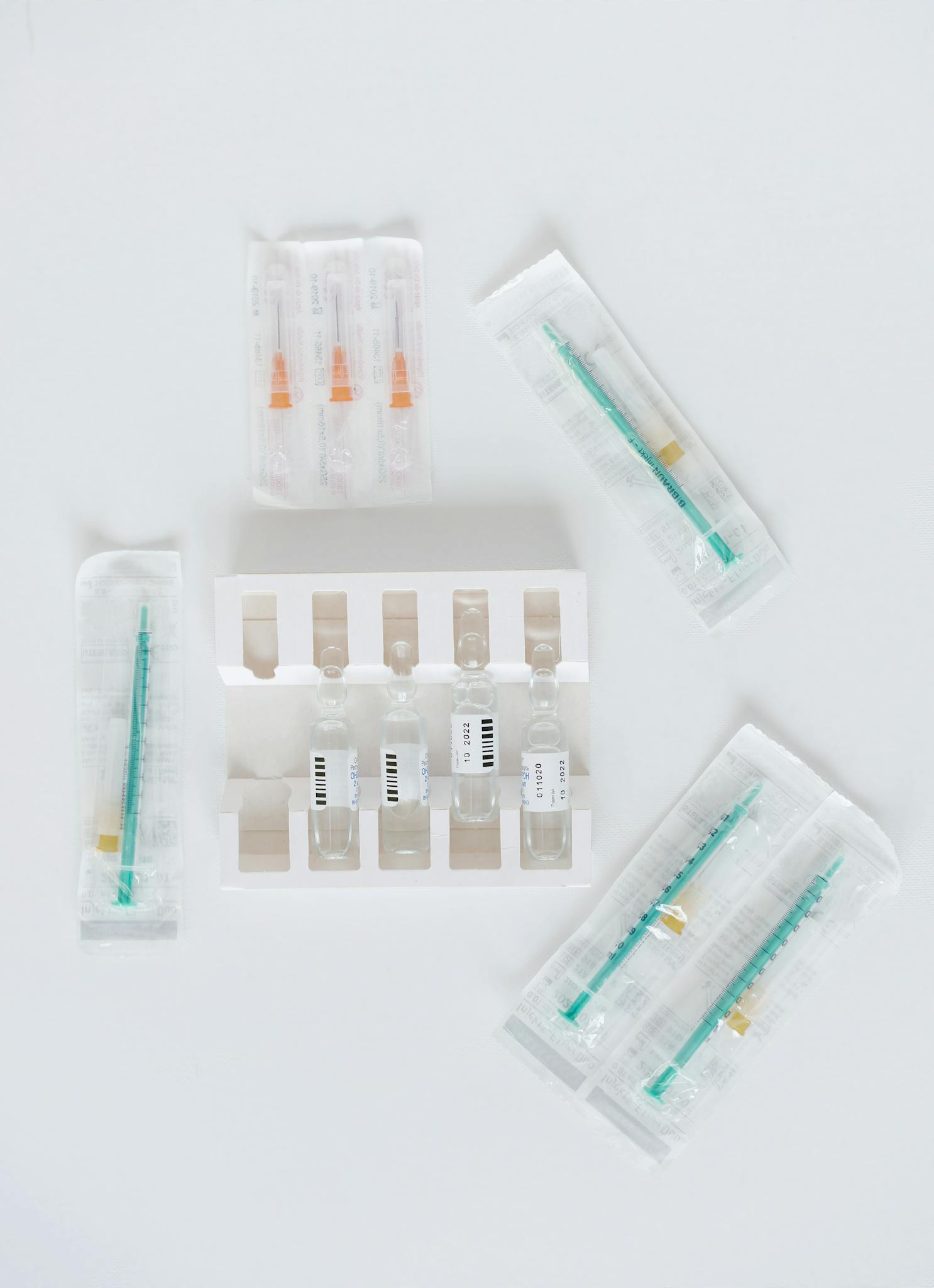 Flat lay of medical syringes and ampules on a white background, ideal for healthcare themes.