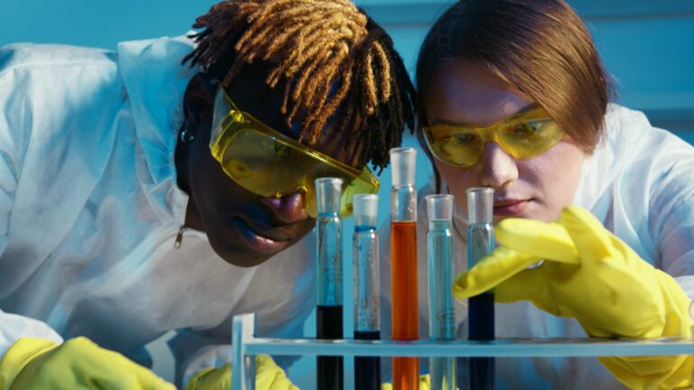 Two scientists work with test tubes in a laboratory, analyzing chemical reactions.